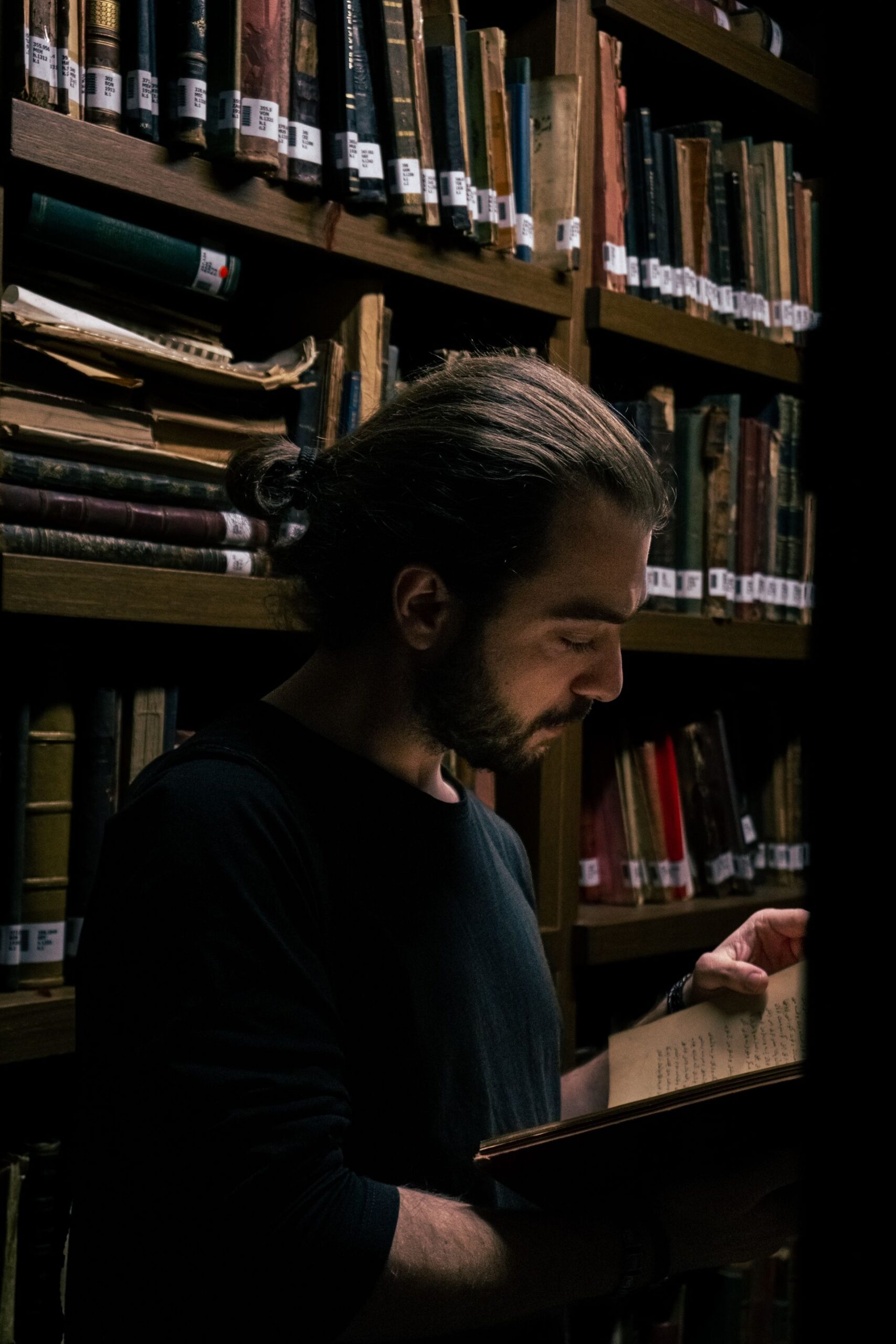 Homem estudando livro antigo manuscrito em biblioteca de obras esotéricas