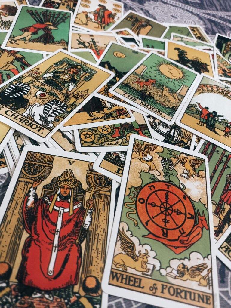Cartas de tarô Rider-Waite espalhadas com destaque para A Roda da Fortuna, A Lua, O Carro e A Sacerdotisa