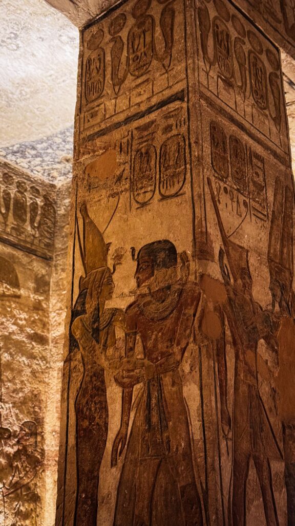 Relevo egípcio antigo com hieróglifos e figuras divinas esculpidas em coluna de templo