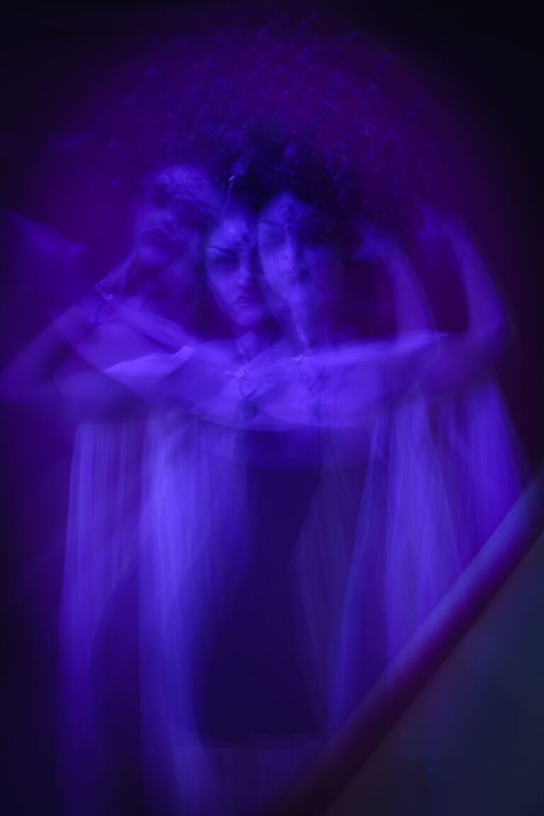 Dupla exposição de silhueta em tons violeta com braços erguidos, criando efeito etéreo e translúcido de desdobramento espiritual