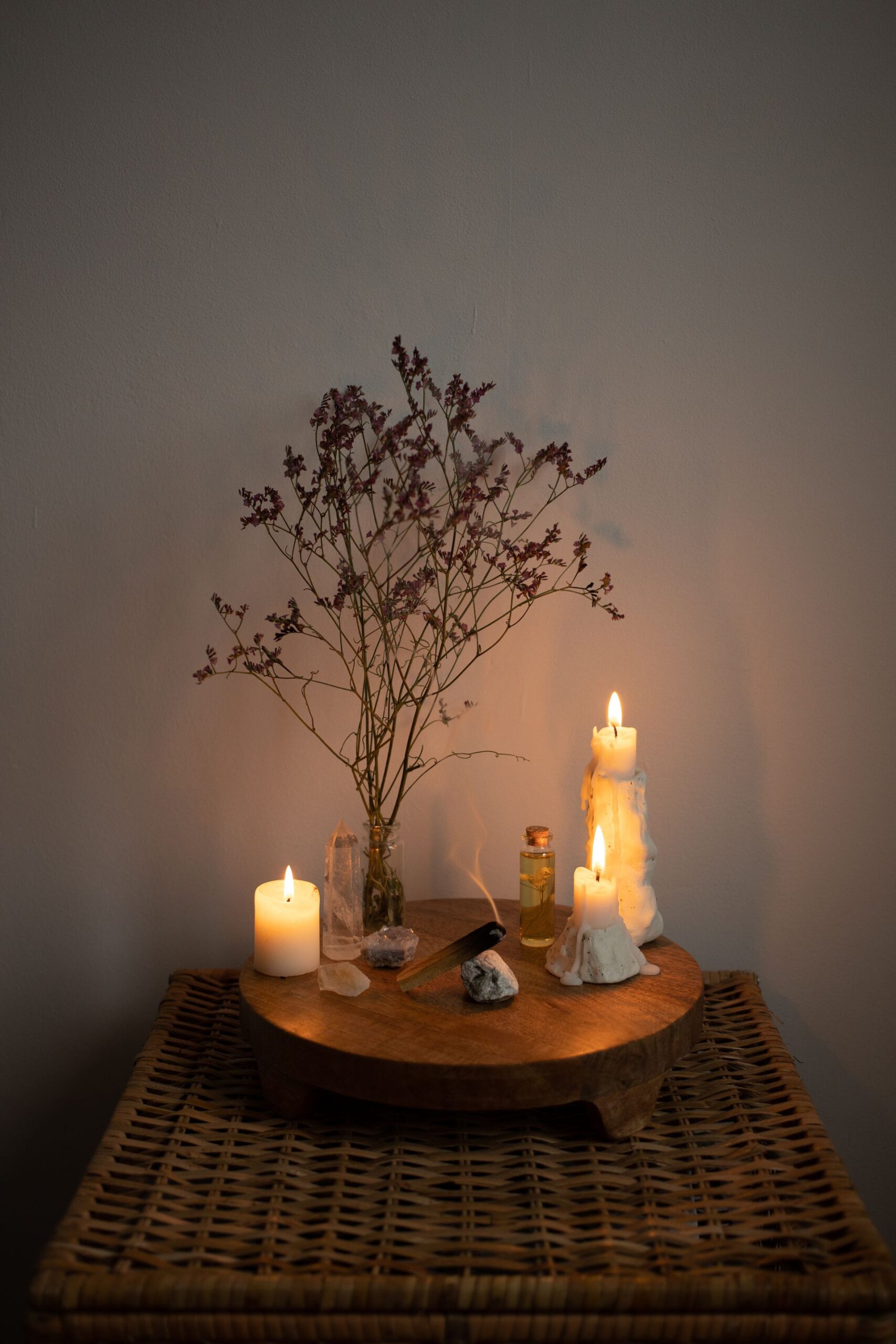 Altar com velas acesas, ramos secos e frasco de vidro, composição que remete aos quatro elementos em ritual
