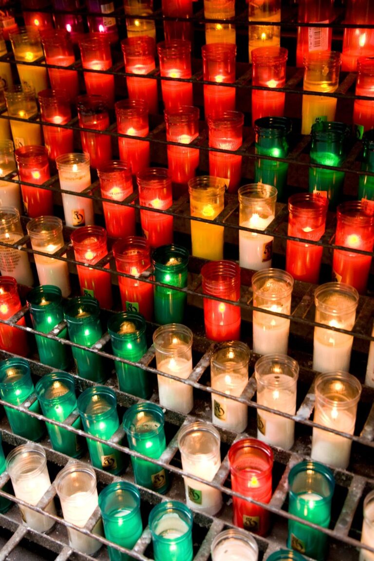 Velas coloridas acesas em suporte de metal, representando as cores usadas em rituais de proteção